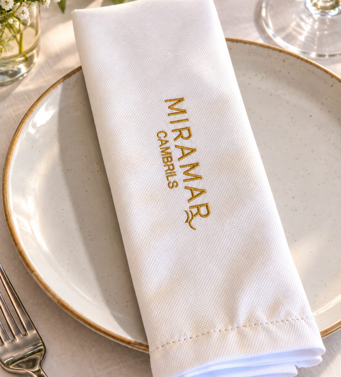 Servilleta Getaria blanca con logo bordado sobre un plato de restaurante
