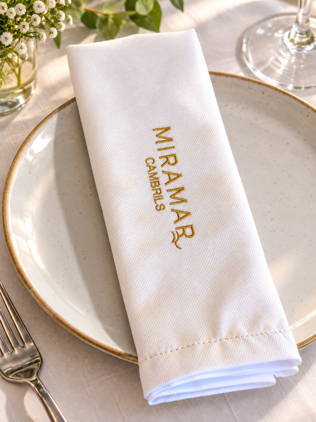 Servilleta Getaria blanca con logo bordado sobre un plato de restaurante